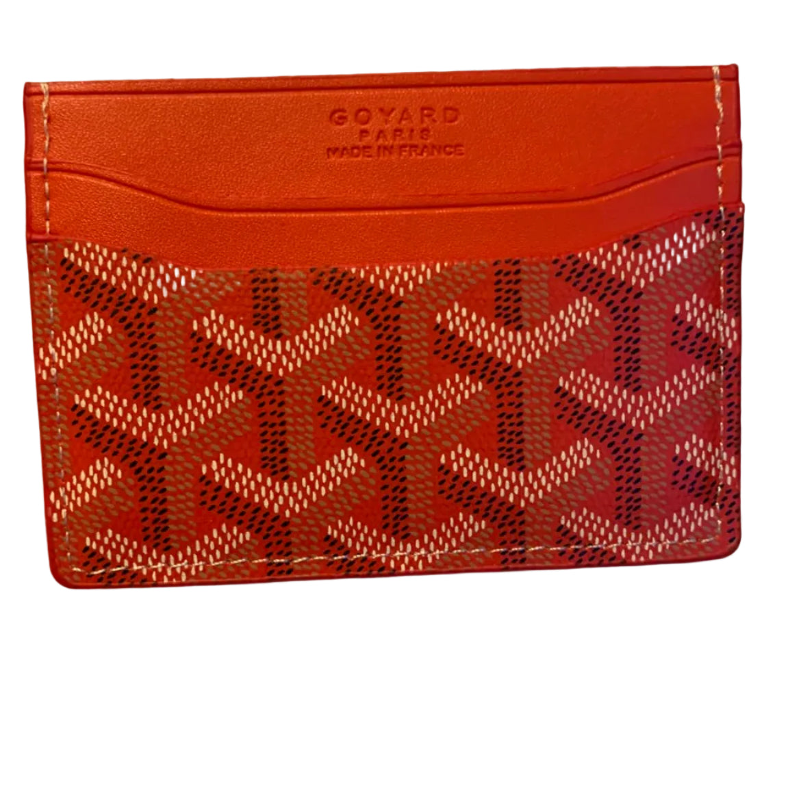 A Goyard card holder wallet in red leather with the signature Goyardine monogram pattern on the front, held by a hand against a plain light background.
